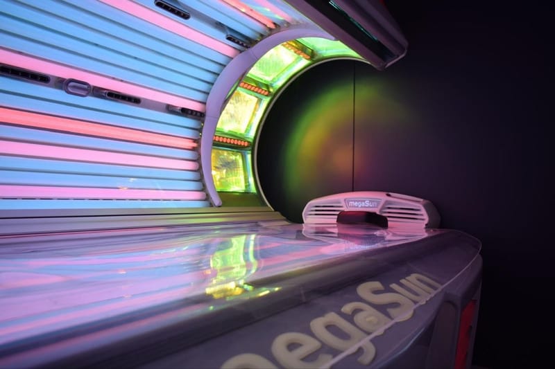 Open MegaSun sunbed with pink, blue and green illuminated tubes